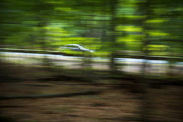 Cars going fast on an interstate road amid forests