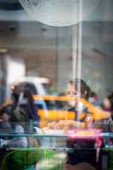 Pretty, young woman eating sushi in a restaurant, having her lunch break, enjoying the food, pausing for a while from her busy corporate/office life (color toned image)