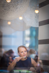 Pretty, young woman eating sushi in a restaurant, having her lunch break, enjoying the food, pausing for a while from her busy corporate/office life (color toned image)