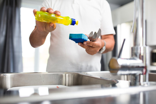 Senior man washing dishes in his modern, bright kitchen
