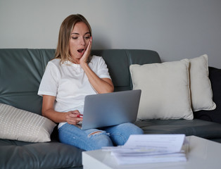 Debt worried young female with laptop seating on the couch