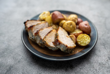 Roasted pork with spices and Parmesan roasted baby potatoes. Close up on a plate. 