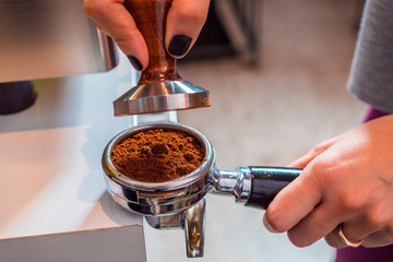 Preparing ground coffee with an espresso tamper, in a portafilter