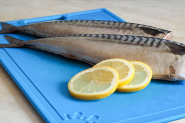 three slices of lemon and two peeled headless mackerel in its raw form on the blue plastic Board ....