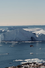Telephoto shot of boat among the icebergs in Disko bay Ilulissat