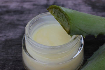 Natural aloe vera face cream on dark vintage wooden background. Homemade beauty product. Organic cosmetic and self-care concept. Top view, copy space.