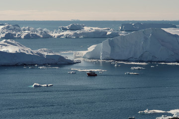 Telephoto shot of boat among the icebergs in Disko bay Ilulissat