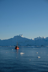 Telephoto shot of boat among the icebergs in Disko bay Ilulissat