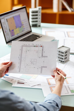 Interior designer working with an apartment plans in a studio, with blueprints and laptop on a table.