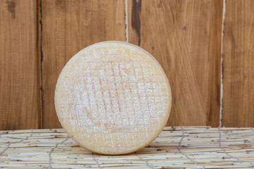 whole round partmesan or pecorino cheese head isolated on wooden background. Fresh dairy product, healthy organic food. Delicious appetizer.