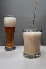 Closeup of pouring gold beer two on grey background for concept design. Summer concept.