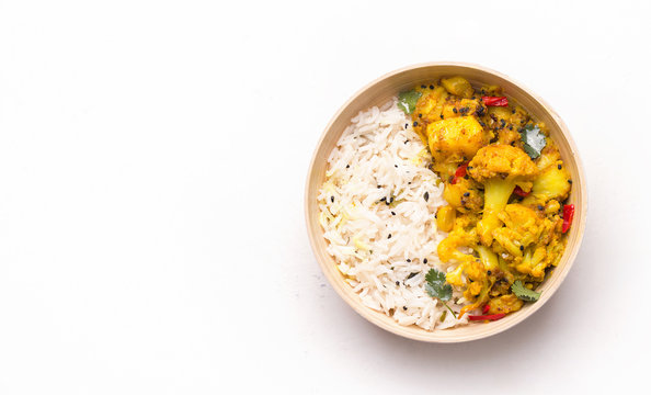 Indian kitchen. Gobi aloo cauliflower dish with rice in a bowl on a white background. Copy space