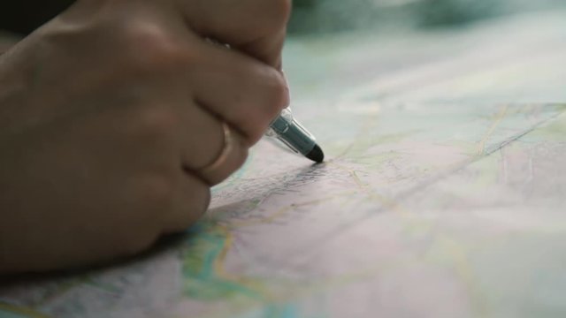 girl draws with felt-tip pen a line on a road map