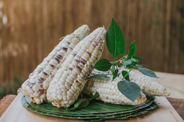 Raw, waxy corns on banana leaves.