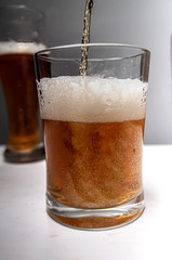 Closeup of pouring gold beer two on grey background for concept design. Summer concept.