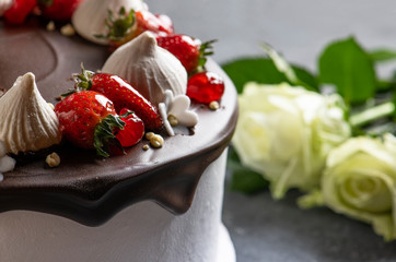 Chocolate cake with fresh strawberry and marshmallows. White roses on the background.