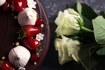 Fototapeta na wymiar Chocolate cake with fresh strawberry and marshmallows. White roses on the background.