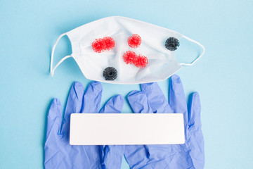 medical face mask, rubber disposable gloves on a blue background, small virus models are in the mask, protection against coronavirus infection, copy space