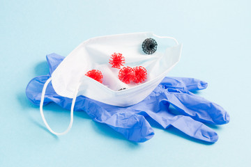 medical face mask, rubber disposable gloves on a blue background, small virus models are in the mask, coronavirus concept, infection protection