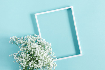 Flowers composition romantic. White gypsophila flowers, photo frame on pastel blue background. Valentine's Day, Easter, Birthday, Happy Women's Day, Mother's day. Flat lay, top view, copy space