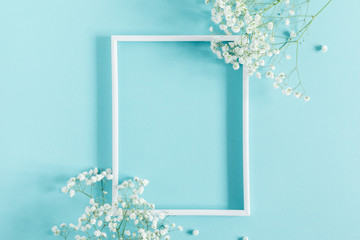 Flowers composition romantic. White gypsophila flowers, photo frame on pastel blue background....