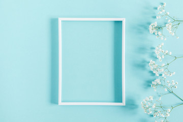 Flowers composition romantic. White gypsophila flowers, photo frame on pastel blue background. Valentine's Day, Easter, Birthday, Happy Women's Day, Mother's day. Flat lay, top view, copy space