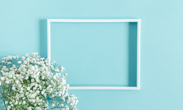 Flowers composition romantic. White gypsophila flowers, photo frame on pastel blue background. Valentine's Day, Easter, Birthday, Happy Women's Day, Mother's day. Flat lay, top view, copy space