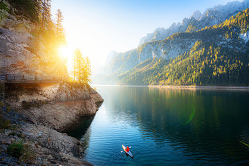 Scenic autumn sunrise scenery with adventurer kayaking in idyllic mountain lake in the Alps in fall, Austria