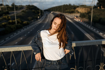 Young pretty girl on the bridge at sunset. Casual style  - 345997147