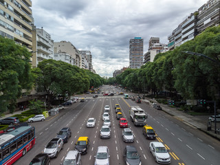 Cars waiting against red light in Av. Libertadores, Buenos Aires with a cloudy sky as background.