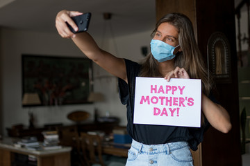 Chica con mascarilla haciéndose un selfie para felicitar el día de la madre durante el confinamiento de COVID-19.