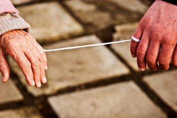 Hands of the old and the young are connected by a white thread among themselves close-up. Hands are tied with white thread. Addiction Conceptual Photography