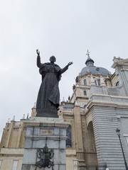 Fototapeta premium Joannes Paulus statue with church at the background in Madrid