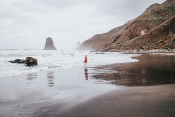 girl runs along the black beach