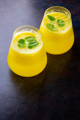 Pineapple cocktail on a dark background. Cold pineapple cocktail with mint. Summer tropical cocktail on a black background. Healthy drink. Top view. Copy space