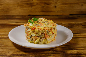 Tasty salad with chicken breast, roasted mushrooms, carrots, grated cheese, eggs and mayonnaise on wooden table