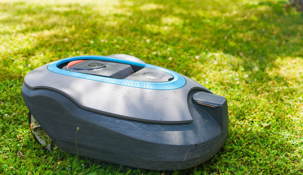 New Modern Robotic Lawnmower On The Grass. Gardener Equipment. 