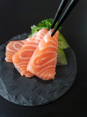 Salmon sashimi picked up with chop sticks
