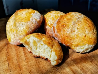 Close-up of fresh pastries: buns on a wooden cutting board. One bun in a section, a magnificent dough is visible. Homemade baking. Curd buns.
