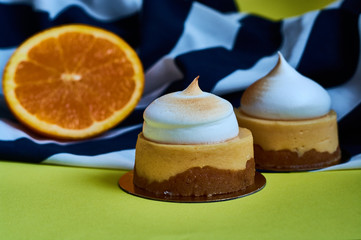 Dessert meringue, citrus tart on a lemon background with an orange striped cloth. Delicious sweets and pastries. Tartlet.