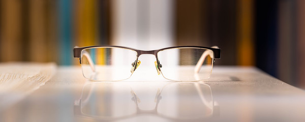 Okulary wyizolowane na tle książek. Okulary leżąna stole © Michal45