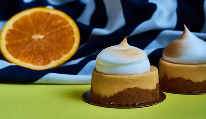 Dessert meringue, citrus tart on a lemon background with an orange striped cloth. Delicious sweets and pastries. Tartlet.