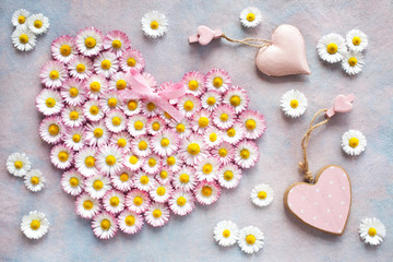 Heart from flowers of daisies and decors of hearts on a colored background, greeting card.