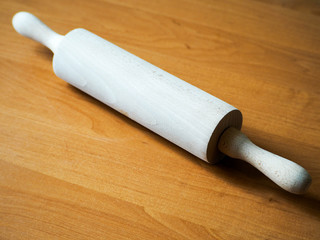 beige wooden rolling pin on the background of the table before baking . cooking appliance