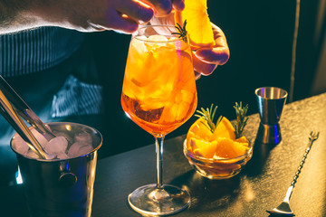Bartender adding orange slice on Aperol Spritz cocktail glass