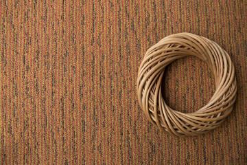 A round wreath made of natural vines lies on a background of brown vertical striped jacquard fabric. View from above. Copy space. Close-up. Space for text.