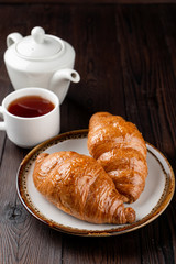 Traditional french croissants of puff-dough and butter on dark wooden table