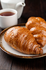 Traditional french croissants of puff-dough and butter on dark wooden table, close up