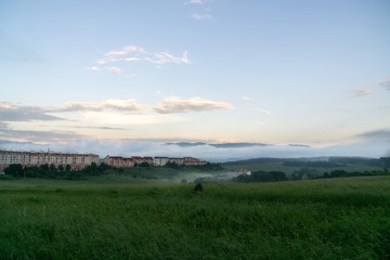 Sunrise and sunset, beautiful clouds over the meadow, hills and buildings in the town. Slovakia