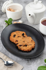American crunchy chocolate cookies with powdered sugar on top, served with tea in white single tea-set